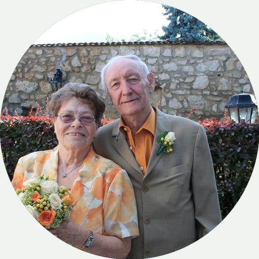 Älteres, feierlich gekleidetes Ehepaar schaut lächelnd in die Kamera.