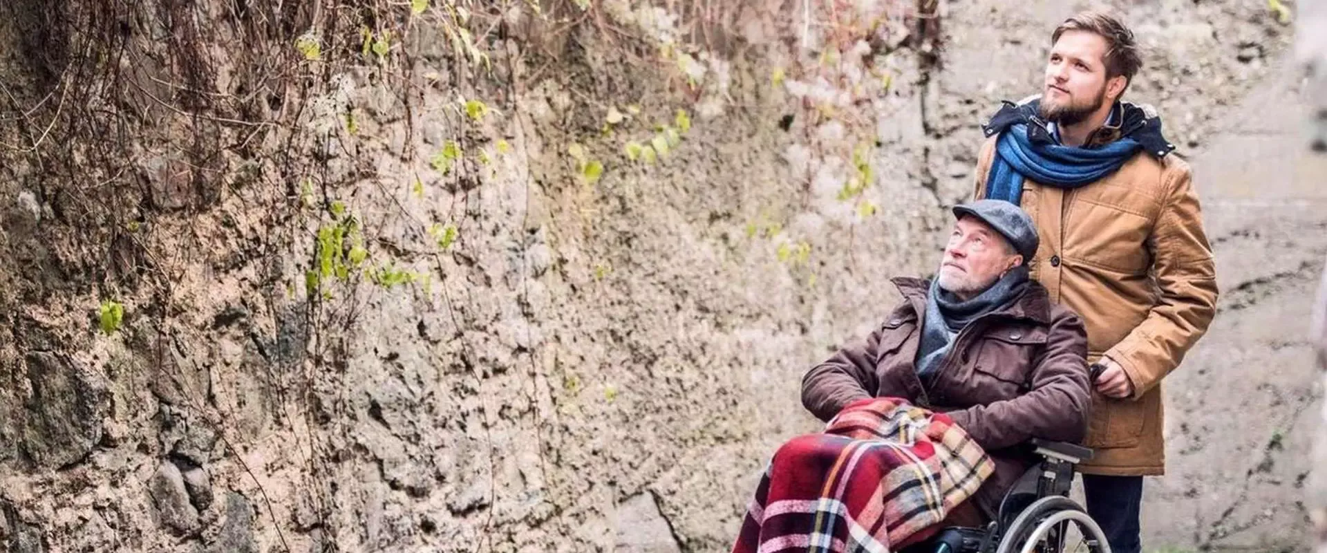 Mann schiebt Rentner im Rollstuhl