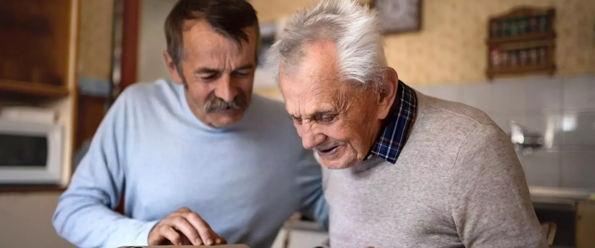 Sohn schaut mit älterem Vater im Fotalbum