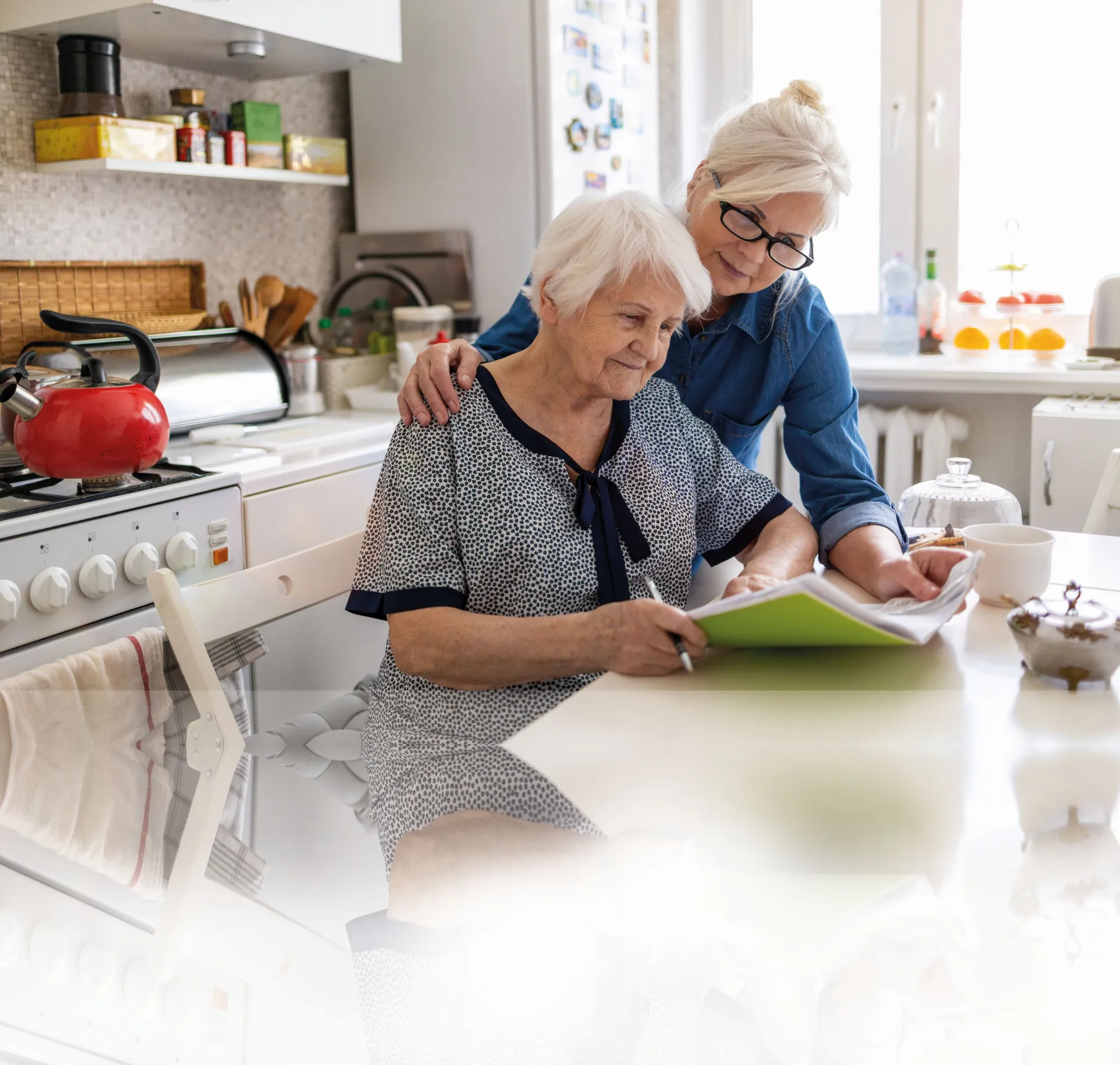 Zwei Frauen sind am Tisch und schauen sich Unterlagen an
