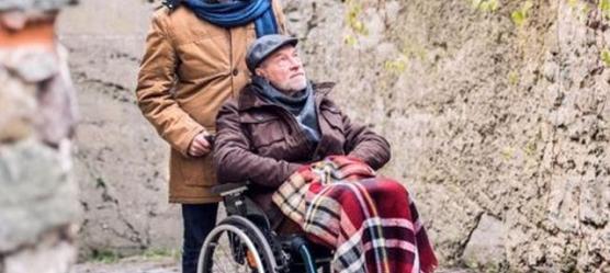 Bild Mann schiebt Rentner im Rollstuhl