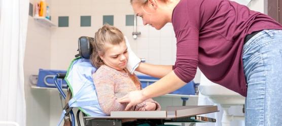 Bild Frau wäscht Kind im Rollstuhl