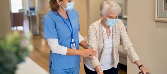 Pflegerin mit Frau am Rolator