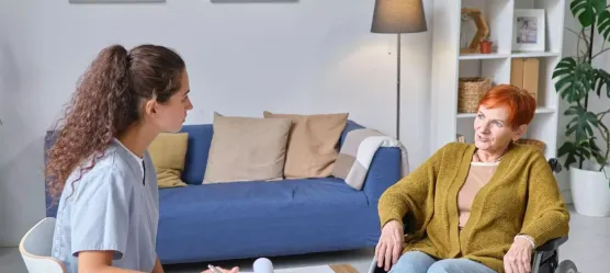 Pflegerin bespricht sich mit Frau im Rollstuhl