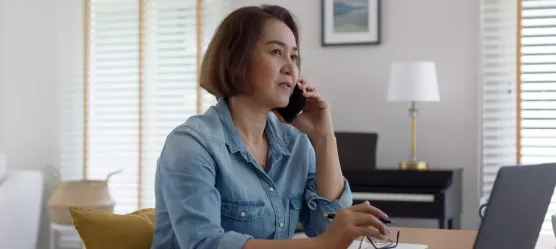 Bild: Frau mit Handy am Laptop