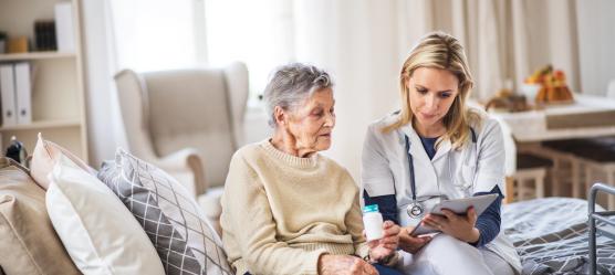 Pflegekraft bespricht mit Heimbewohnerin den Medikationsplan