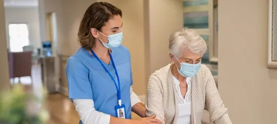 Pflegerin mit Frau am Rolator