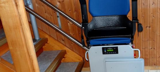 Eingebauter blauer Treppenlift am Treppenanfang einer Wohnung, ohne Person