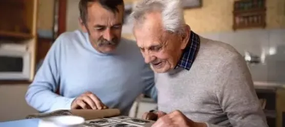 Sohn schaut mit älterem Vater im Fotalbum